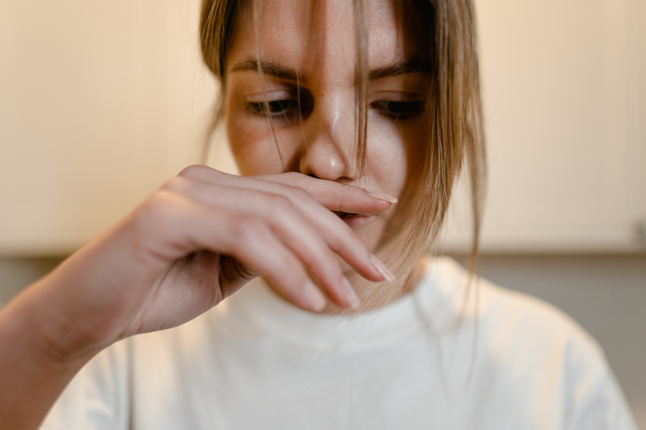 Woman in White Shirt with Hand Over Lips 